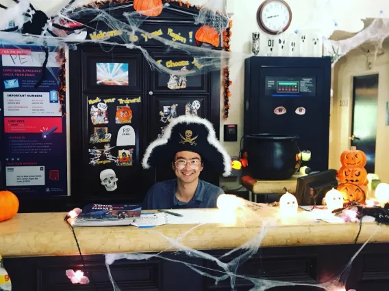 Desk Assistant dressed as pirate on Halloween behind dorm front desk.