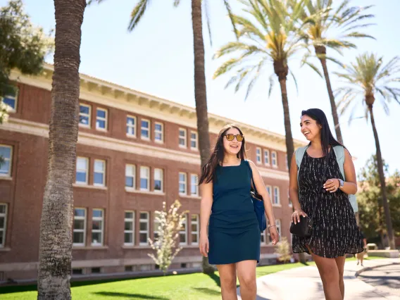 Two students talking in front of a building