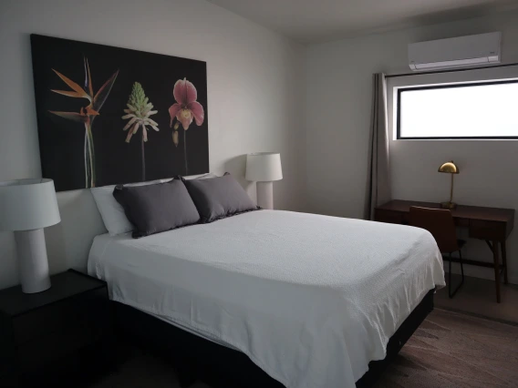 University rowhouse primary bedroom featuring queen bed, two nightstands, and desk