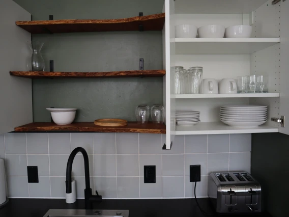 University rowhouse kitchen featuring glassware, plates, bowls, toaster and shelving