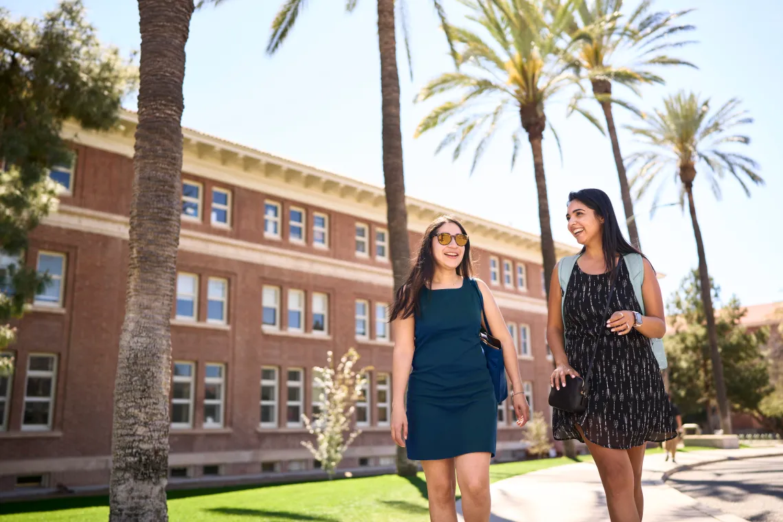 Two students talking in front of a building