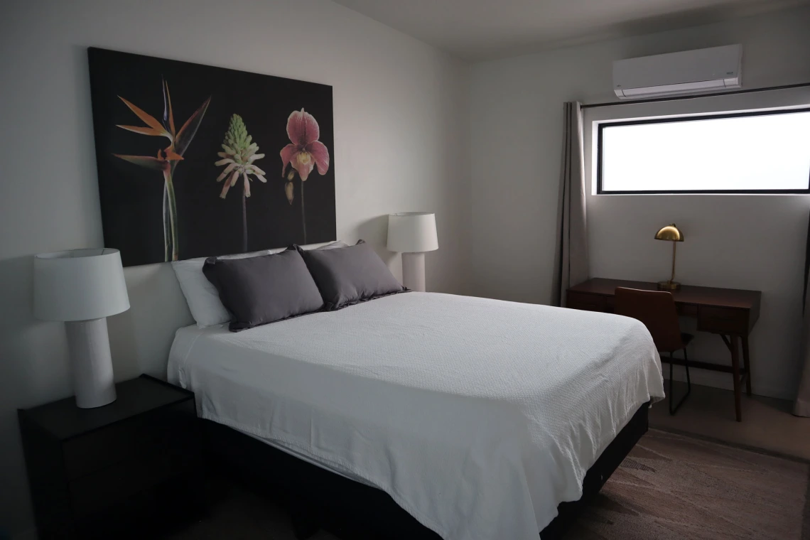 University rowhouse primary bedroom featuring queen bed, two nightstands, and desk