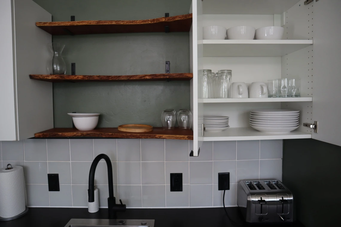 University rowhouse kitchen featuring glassware, plates, bowls, toaster and shelving