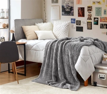 picture of one side of a student dorm room featuring a decorated wall and ample bedding